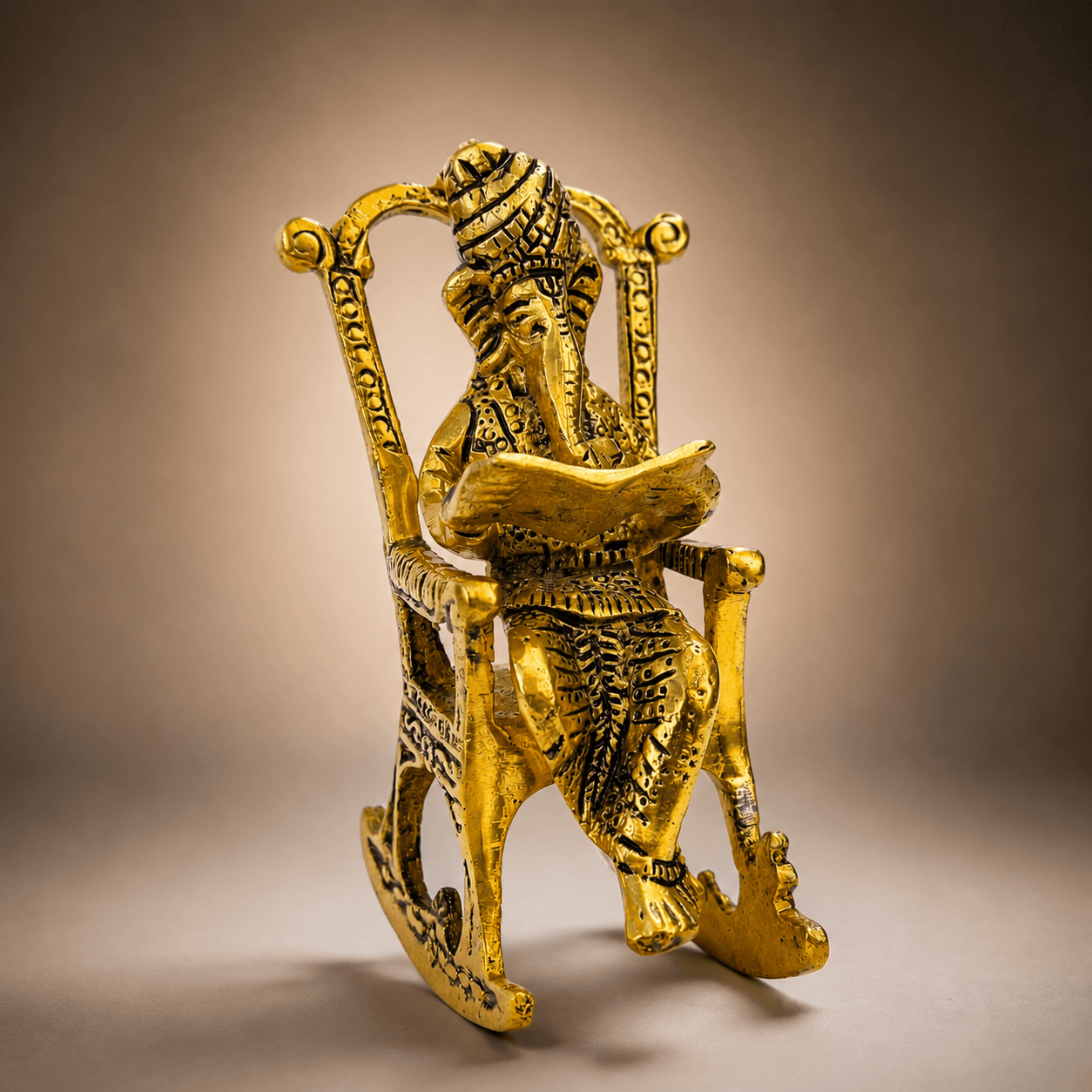 Gold Plated Ganesha Idol Reading Book on Rocking Chair - Plain Background